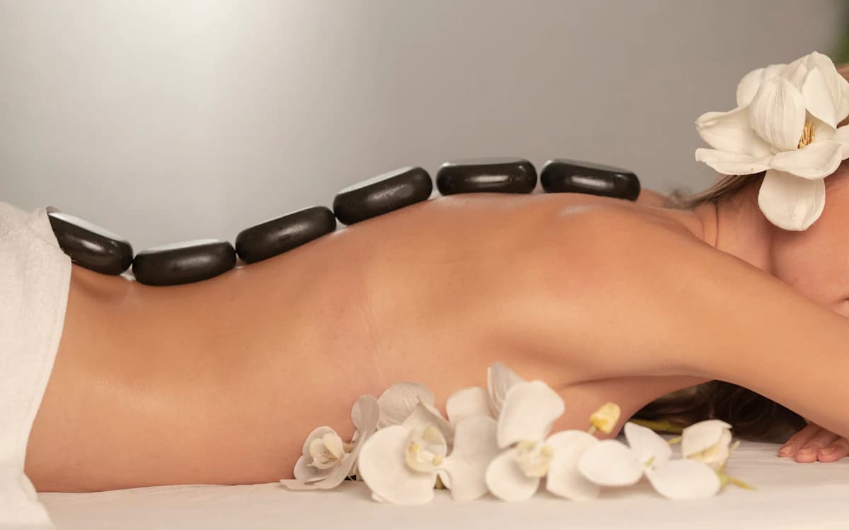 Batu vulkanik hangat ditata di punggung saat sesi hot stone massage