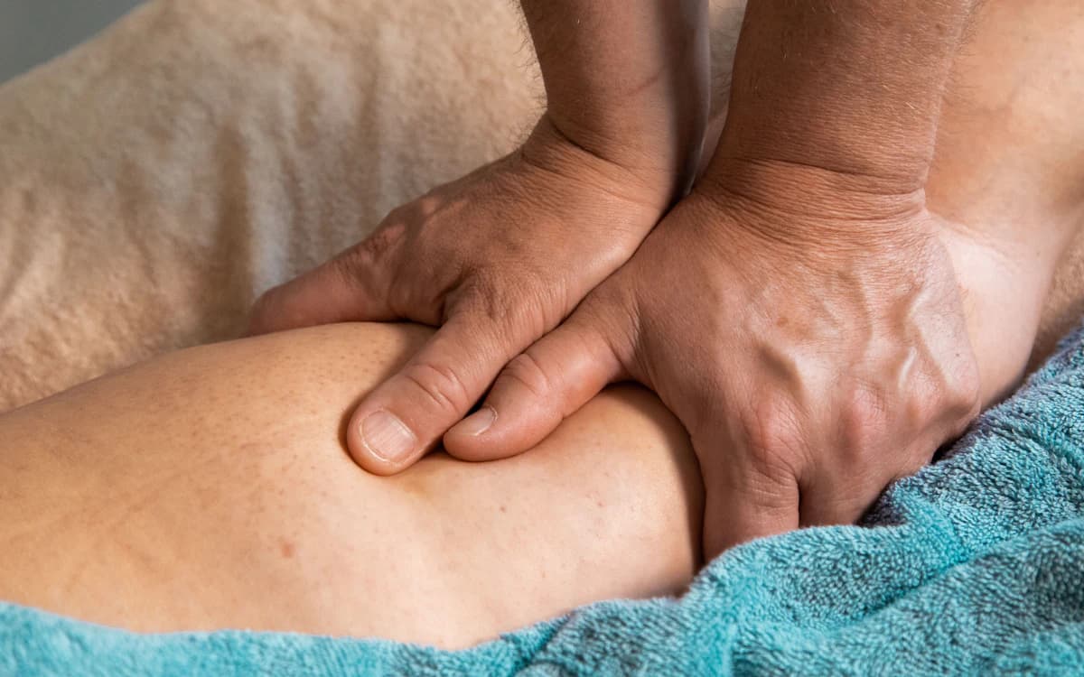 Terapis memijat otot kaki atlet setelah sesi latihan