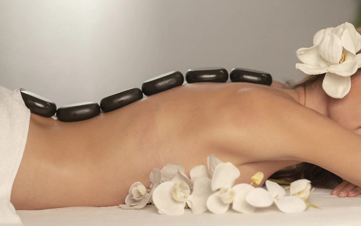 Batu vulkanik hangat ditata di punggung saat sesi hot stone massage
