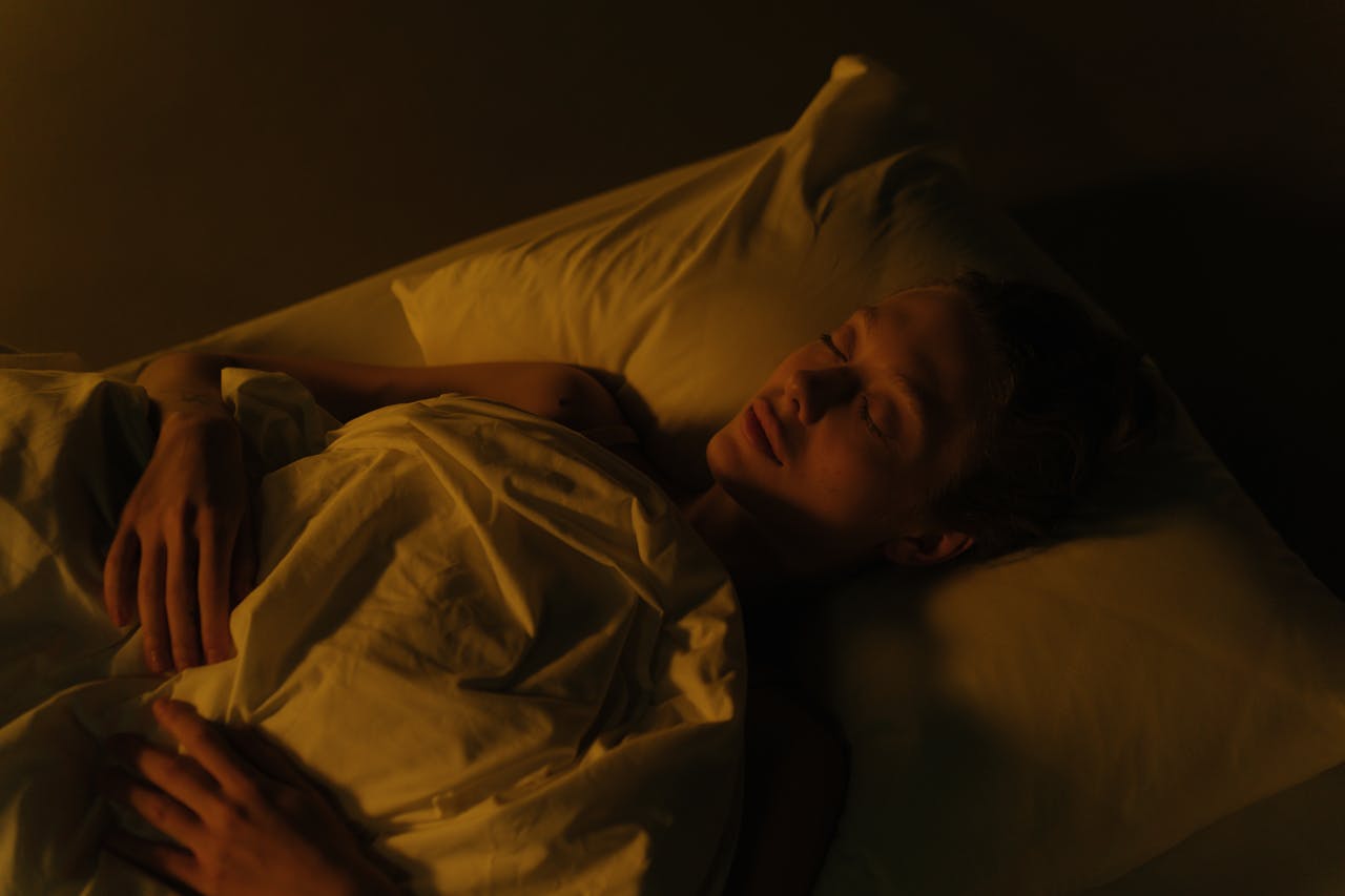 seorang wanita tidur dikamar yang gelap dengan lampu remang warna oranye hangat